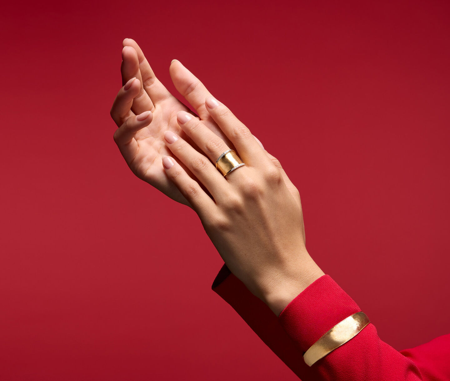 Marco Bicego gold Lunaria jewellery on a red background.